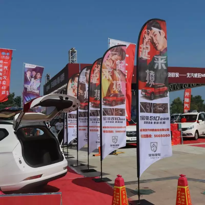 Baojun 510 auto car show: red SUV promo feather flags at outdoor exhibition.