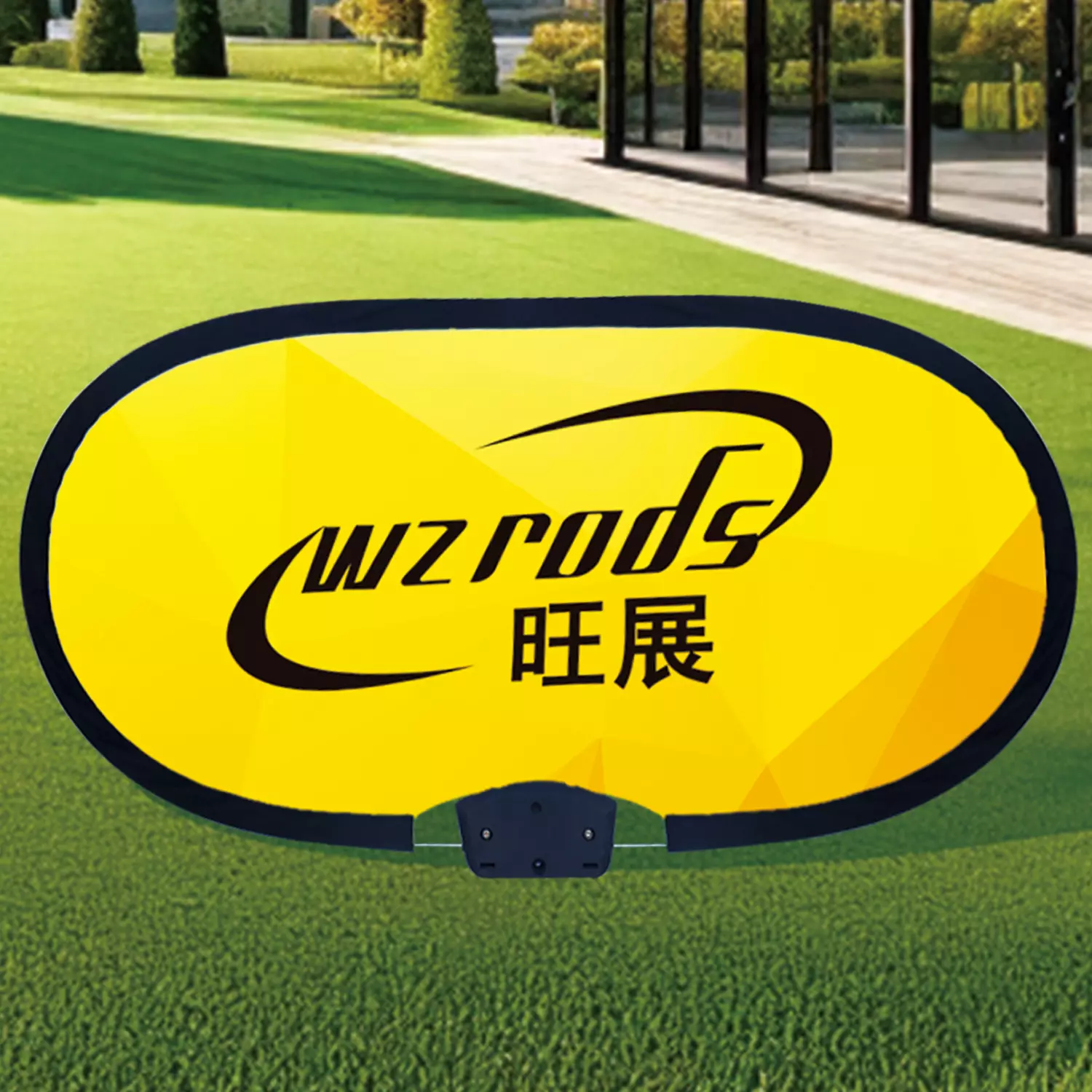 Yellow oval WIZRODS/旺展 banner mounted on grass using ground pegs for soft surfaces. Black text on high-visibility yellow background, ideal for outdoor events and golf course signage.