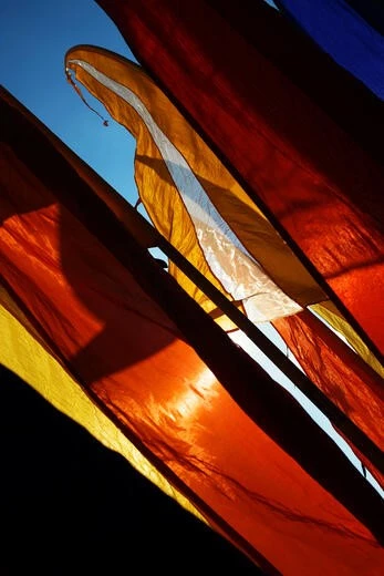 Vibrant orange and red Balinese prayer flags under sunlight Bright orange and red prayer flags inspired by Balinese cultural motifs under sunlight.