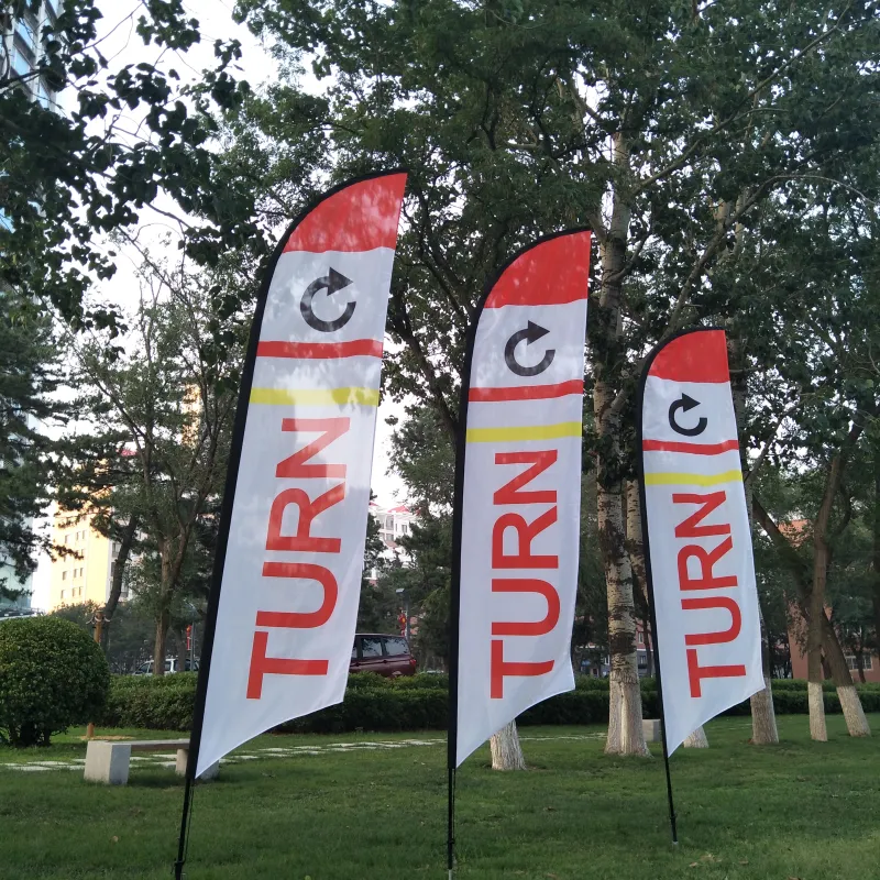 Three white and red beach flags with 'TURN' signs in a park setting.