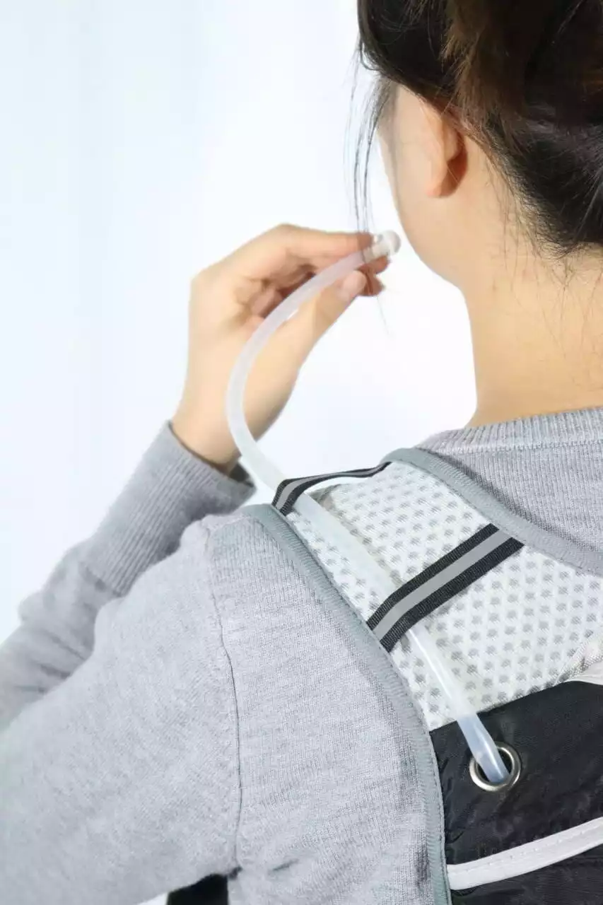 adjusts a hydration tube attached to a marathon pacer flag backpack, highlighting ergonomic design and functional accessories.