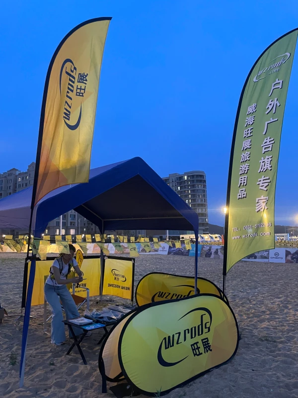Beach promotional setup with pop-up tent, feather flags and cafe barrier at dusk