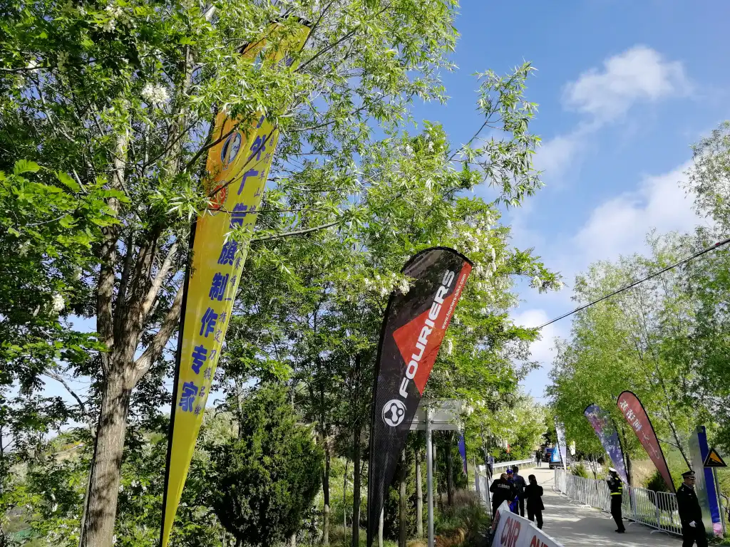 WZRODS partner FOURIERS teardrop flags lining tree-shaded event pathway