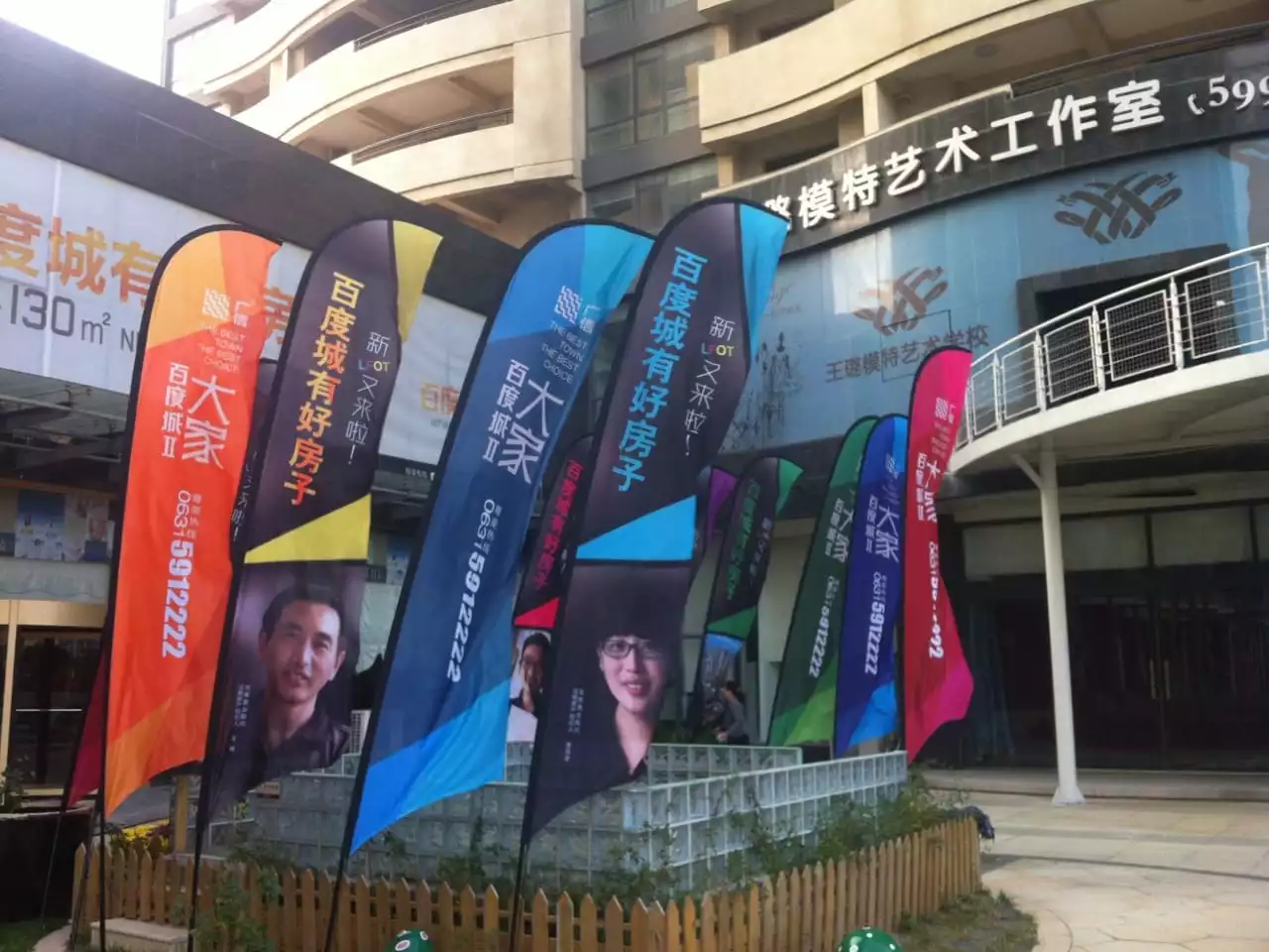 Real estate feather flags advertising,Colorful personalized feather flagsaround bamboo fence at commercial building.