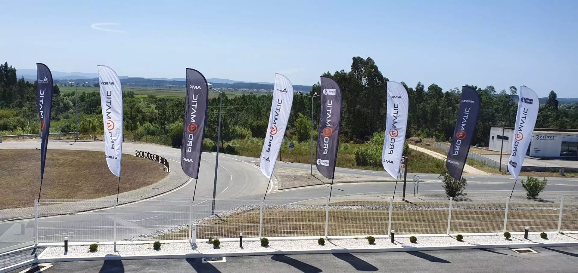 black and white blade flags at outdoor event with mountains, green fields, and clear sky