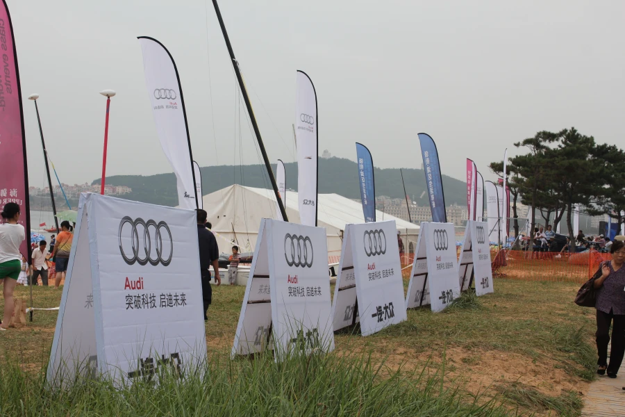 White and blue Audi-themed blade flags at outdoor brand event with tents and mountain backdrop