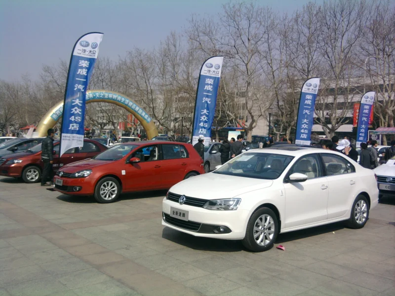 Red Volkswagen cars at dealership with blue razor flags, outdoor auto promo display.