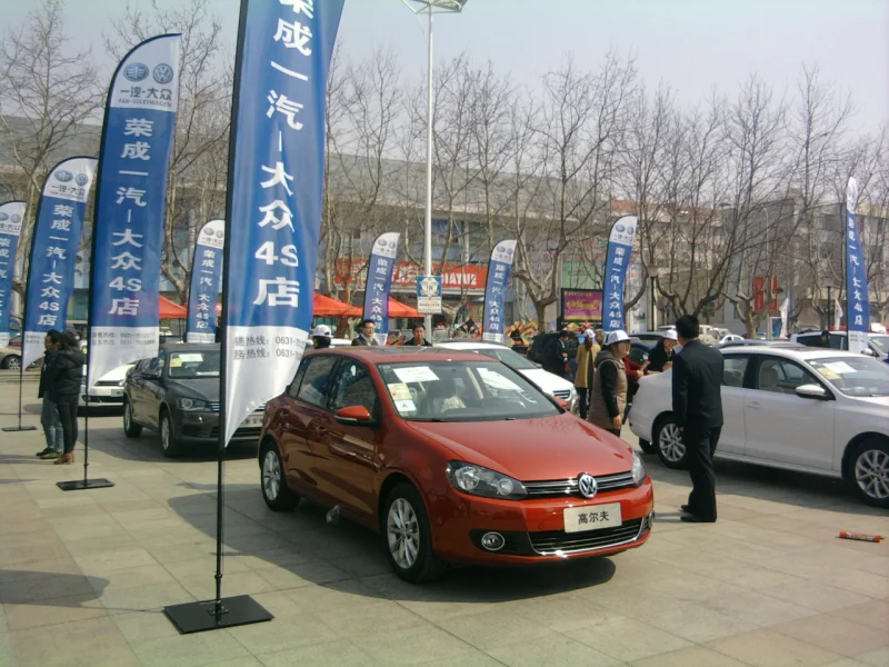 Red Volkswagen Golf at 4S store with blue razor flags, outdoor marketing banners.