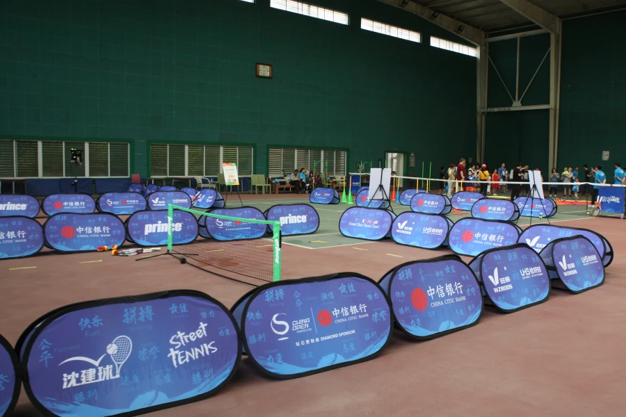 Pop Up Banners(2019 China Tennis Junior) Indoor tennis court setup with blue sideline banners (China Citic Bank, Prince) and sports equipment, ready for an event.