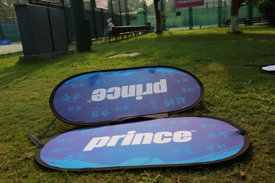 Pop up A Frame Banners Blue 'prince' sideline banner on grass, showcasing brand visibility in an outdoor setting.