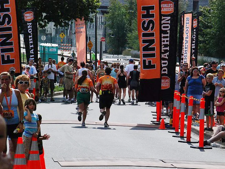 DUATHLON finish line with orange/black portrait flags - World's largest race at Mill Ruins Park