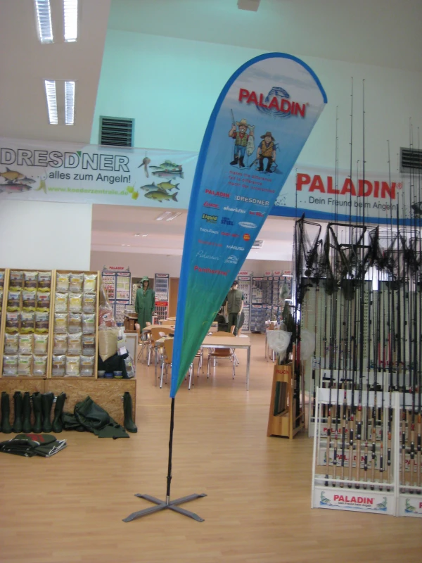 PALADIN branded teardrop flag inside DRESDNER fishing store with rod displays
