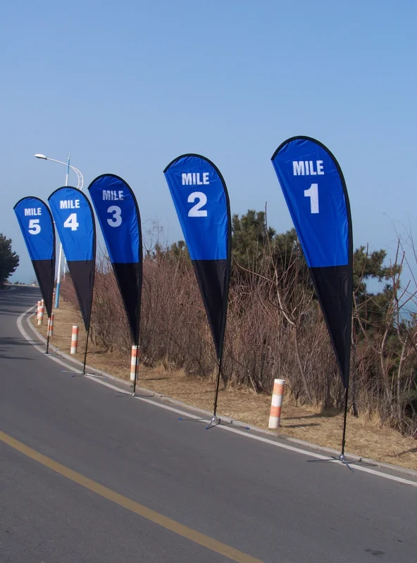 Sequential blue teardrop banners (MILE 5-1) along curved highway with safety markers