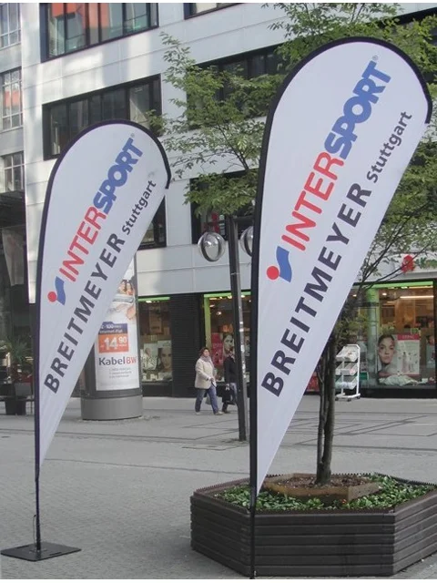 White INTERSPORT teardrop banners mounted in Stuttgart city planters near pedestrian walkway